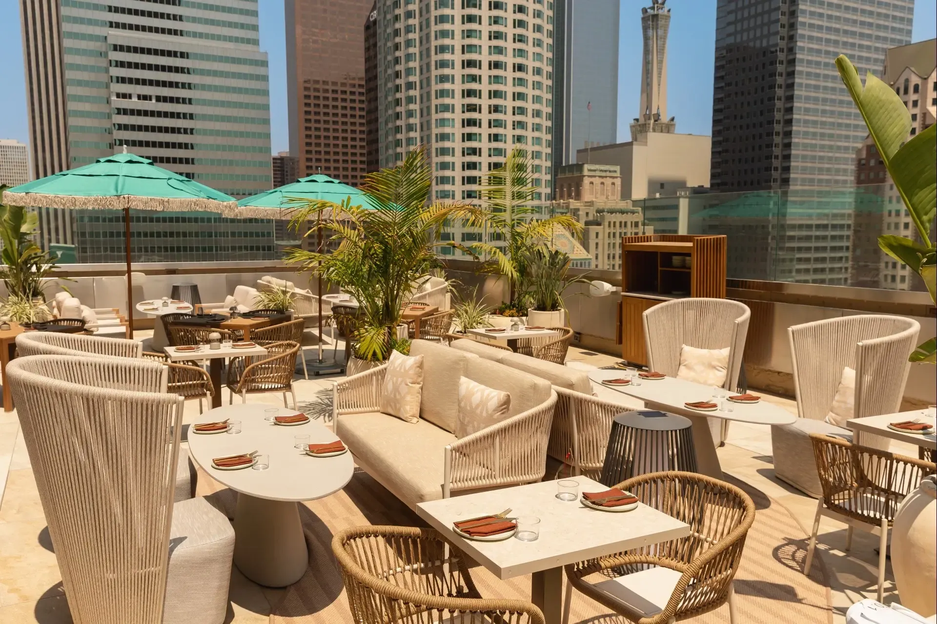 Rooftop dining tables with woven chairs and a high-back rope settee
